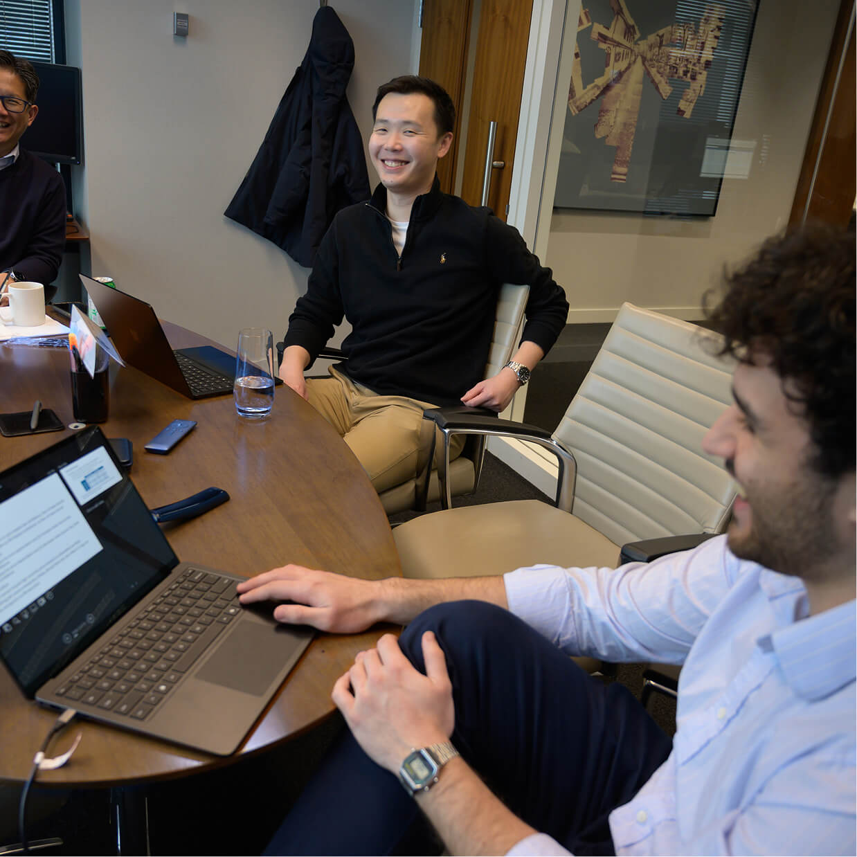 Q Team members sitting around a conference table sharing a moment of laughter.