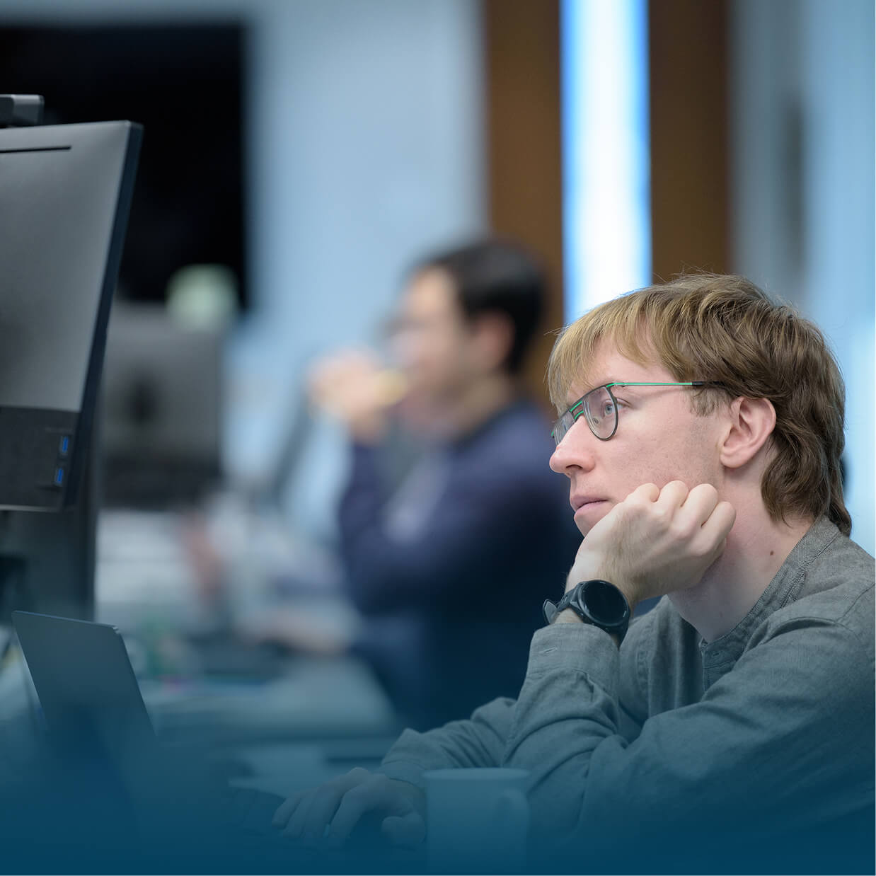 A person wearing glasses and looking at their desktop monitor.