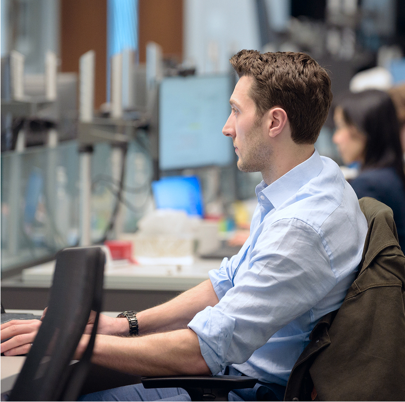 A side profile view of a Q Team member looking at their desktop.